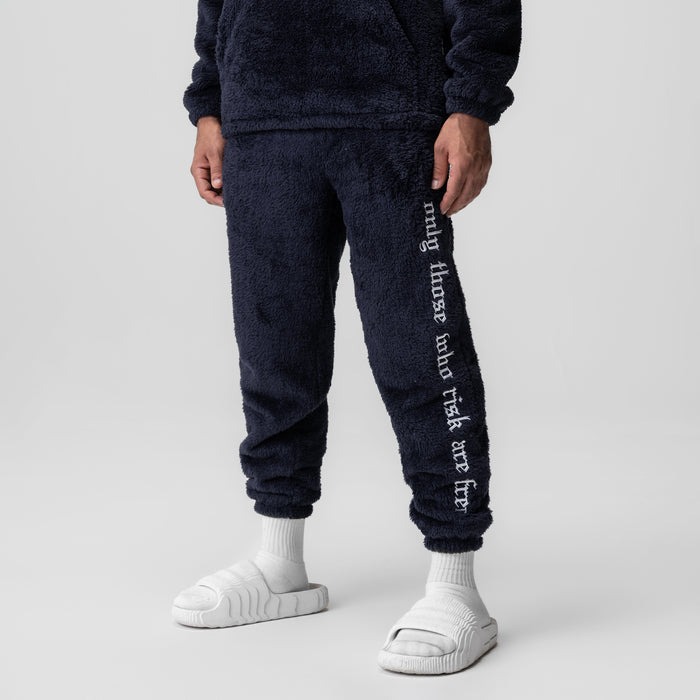 Sherpa Recovery Sweats in navy with white text down the leg, worn with white socks and slides