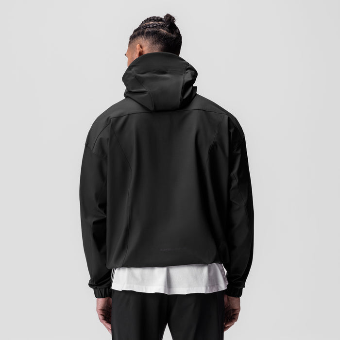 Black weather-ready anorak jacket worn by model, back view, with white shirt visible underneath