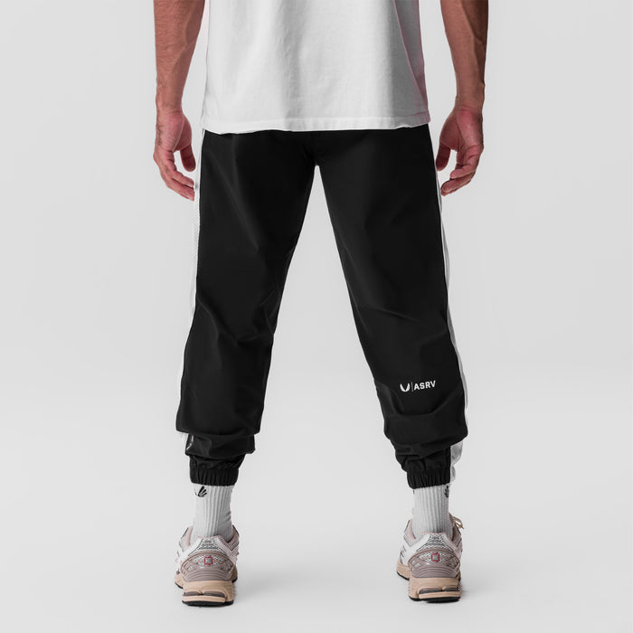 Black ripstop oversized track pant worn by model, back view with white socks and sneakers