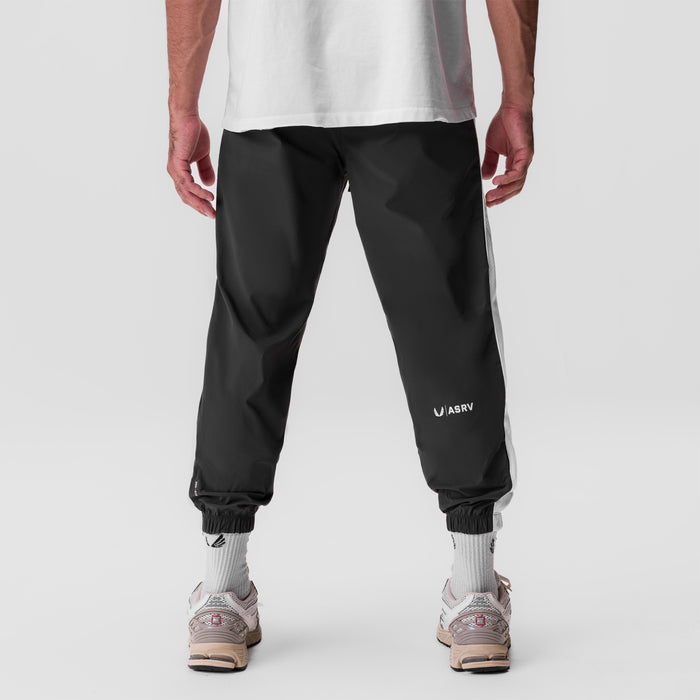 Black ripstop oversized track pant worn by model, back view with white socks and sneakers