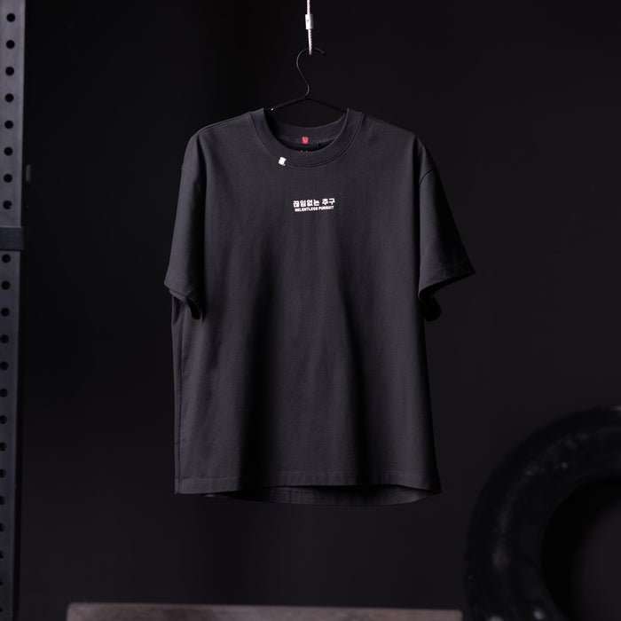 Black Tech Essential Relaxed Tee hanging on hanger against dark background
