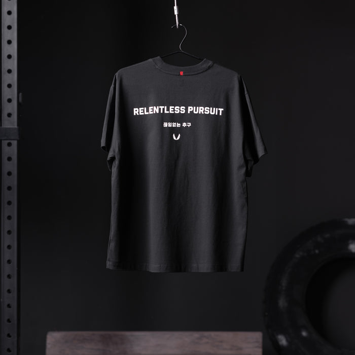 Black Tech Essential Relaxed Tee with 'Relentless Pursuit' graphic, hanging on hanger