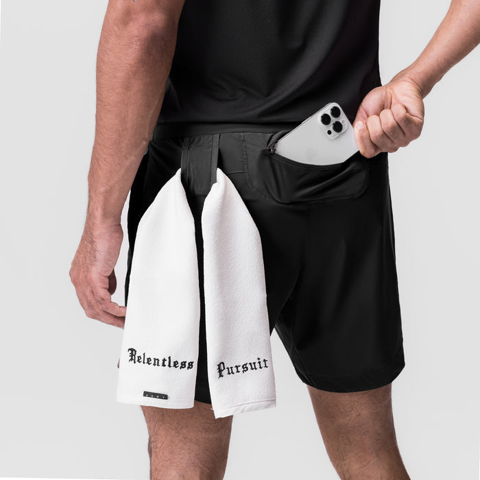 Black Tetra-Lite 7" Linerless Shorts worn by model holding white "Relentless Pursuit" towel