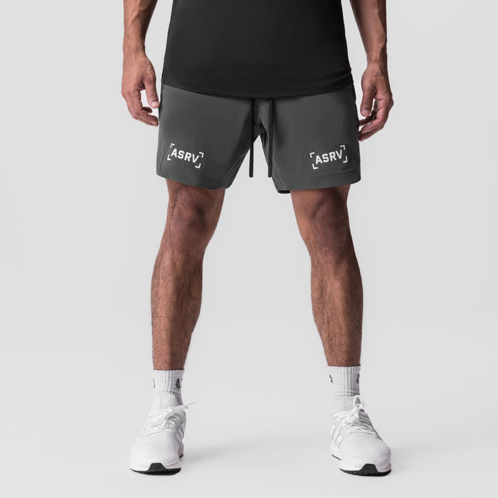 Tetra-Lite 7" Linerless Short in raven, modeled from front with white sneakers and black tank top