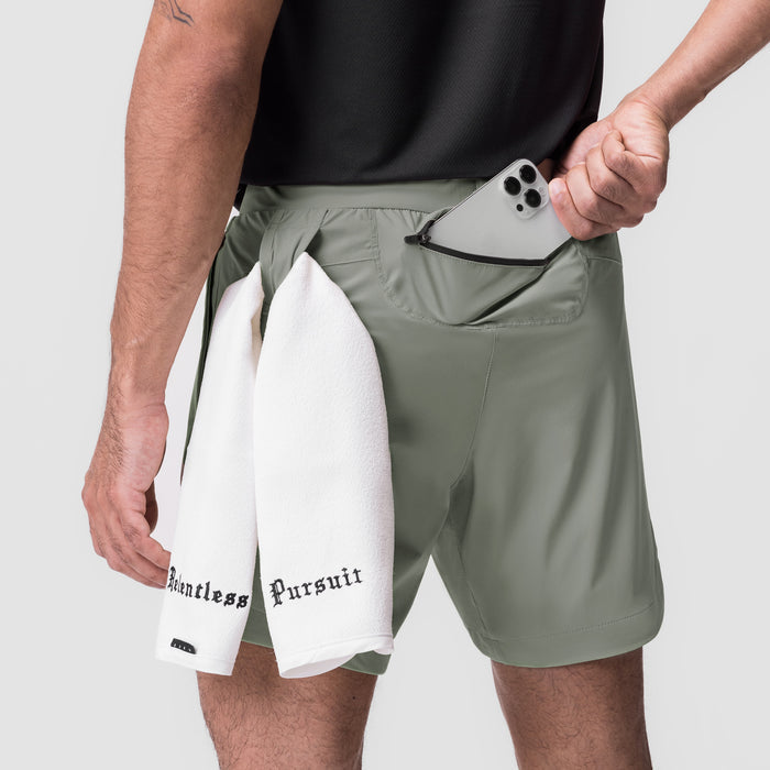 Tetra-Lite 7" Linerless Short in sage with white layered shorts, model holding phone in pocket