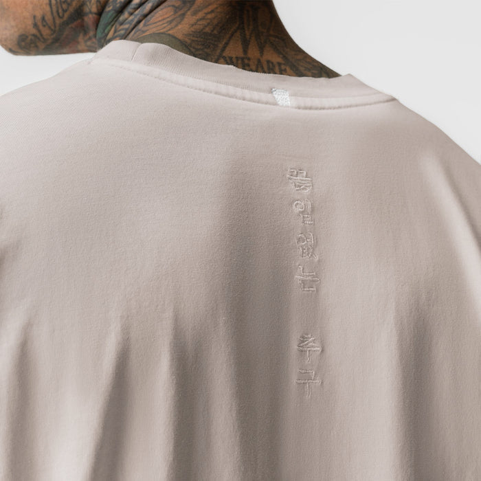 Tech Essential Relaxed Long Sleeve in Faded Chai, back view on model showing embroidered text detail