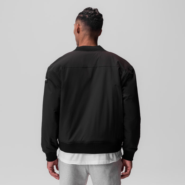 Black ripstop insulated bomber jacket worn by model, back view
