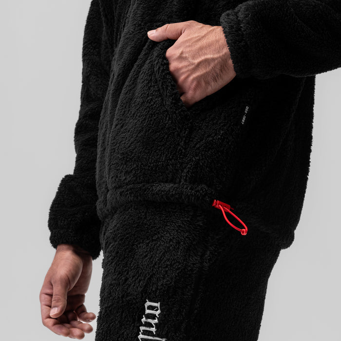 Black Sherpa Recovery Full Zip Hoodie worn by model, showing hand in pocket and red logo detail