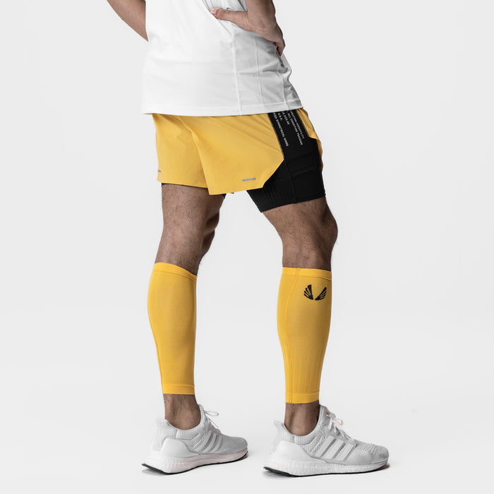 Body-Mapped Calf Sleeve in amber yellow worn on model's legs with matching shorts
