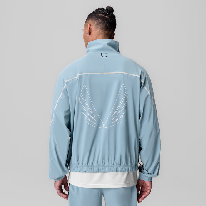 Aerotex Track Jacket in light sky blue worn by model, back view showing wings graphic