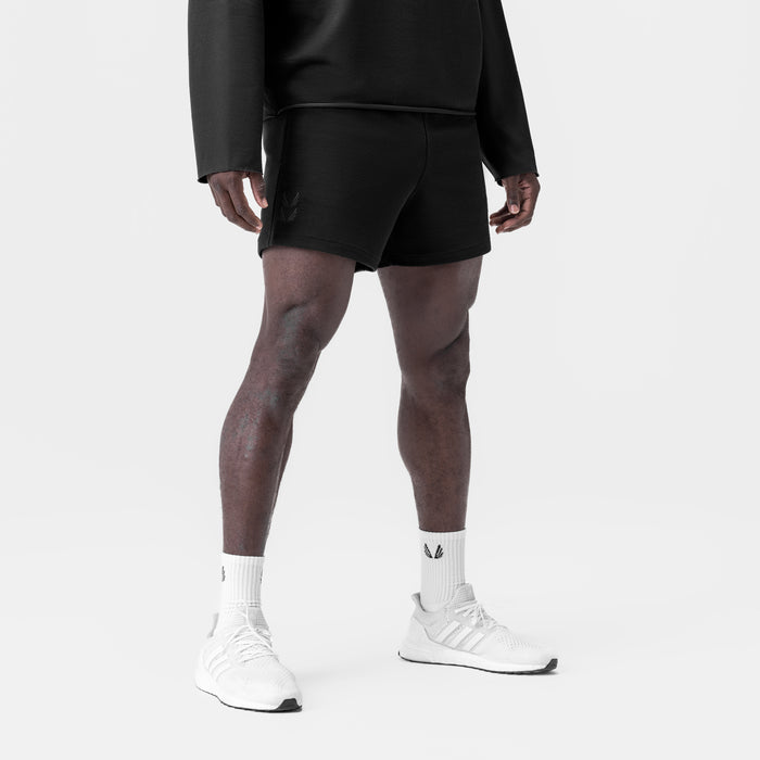 Black waffle knit sweat shorts worn with white socks and sneakers, front view