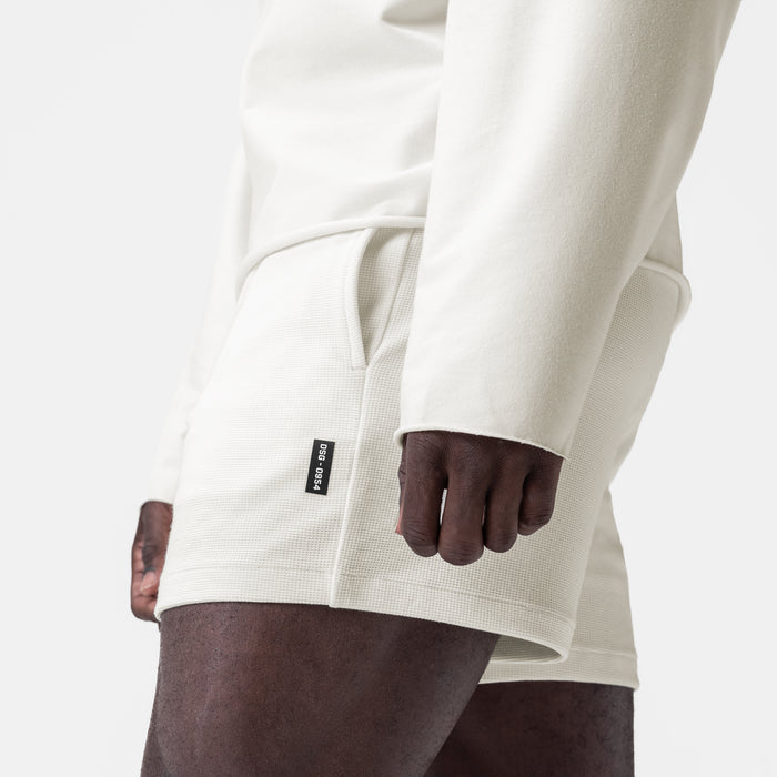 Waffle knit sweat short in cream, worn by model with brown shorts, side view
