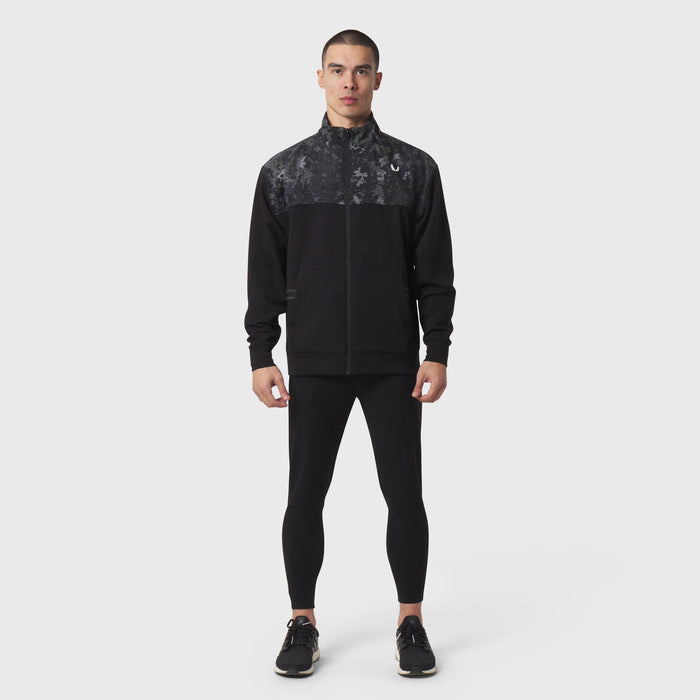 Dri-Core Sidelock Full Zip jacket in black with patterned upper panel, worn with black leggings