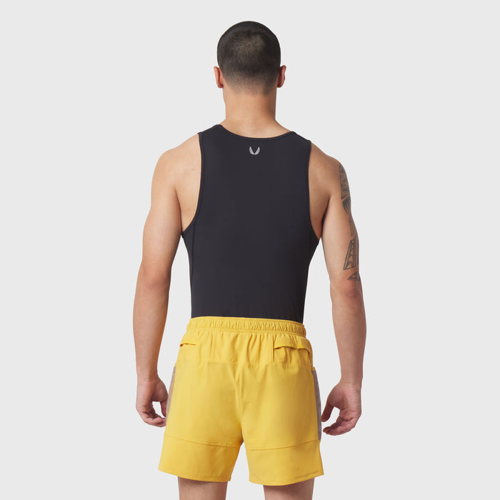 Black LYCRA® ADAPTIV baselayer tank on model, rear view, paired with yellow shorts