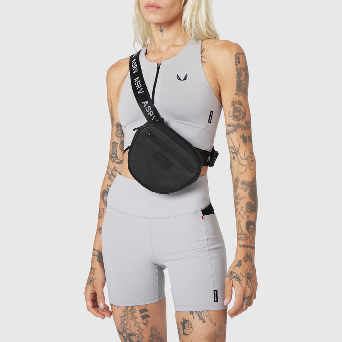 Trail Pack in black, worn as crossbody bag with sports bra and shorts
