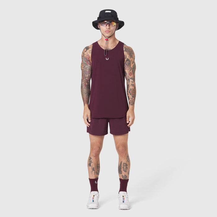 Aerotex Perforated Run Tank in merlot with matching shorts, modeled with white sneakers and black bucket hat