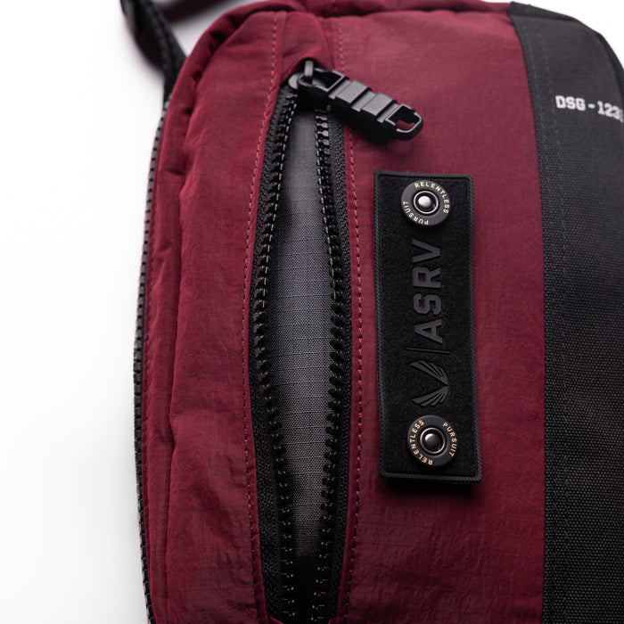 1231 Ripstop Crossbody Bag in Crimson, being worn, detail view of zipper and branding