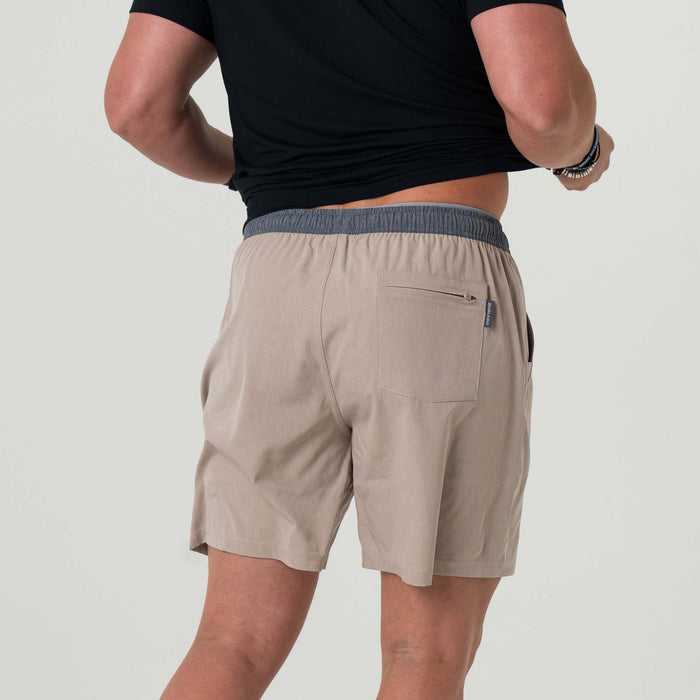 Back view of man wearing beige athletic shorts. There is a back zipper pocket.