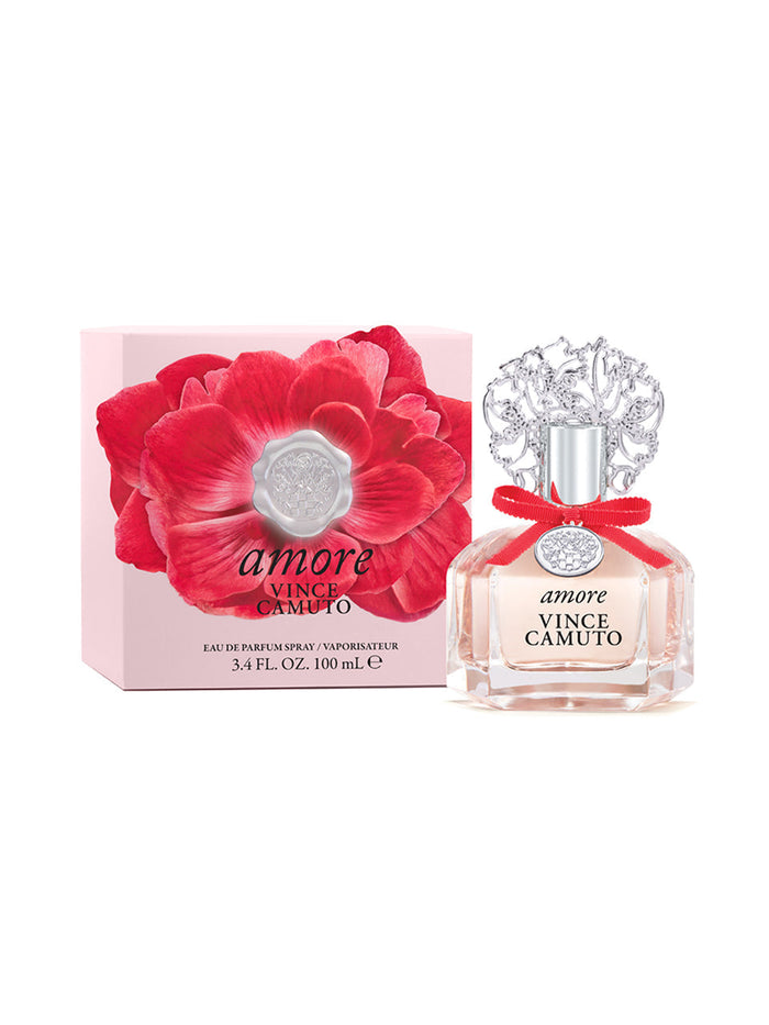 A bottle of Vince Camuto Amore 3.4 oz Eau de Parfum Spray, topped with a silver floral cap, is placed beside its pink box adorned with a bold red flower and the product name. This enchanting fragrance blends sparkling fruits and sensual sandalwood to leave an unforgettable impression.