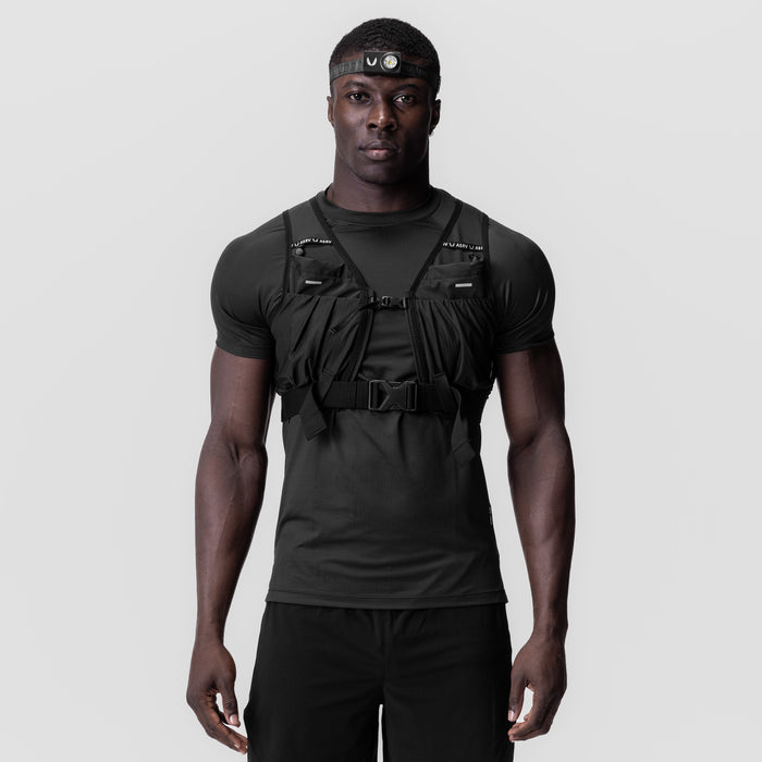 Black tactical vest worn over black t-shirt with headlamp, front view on model