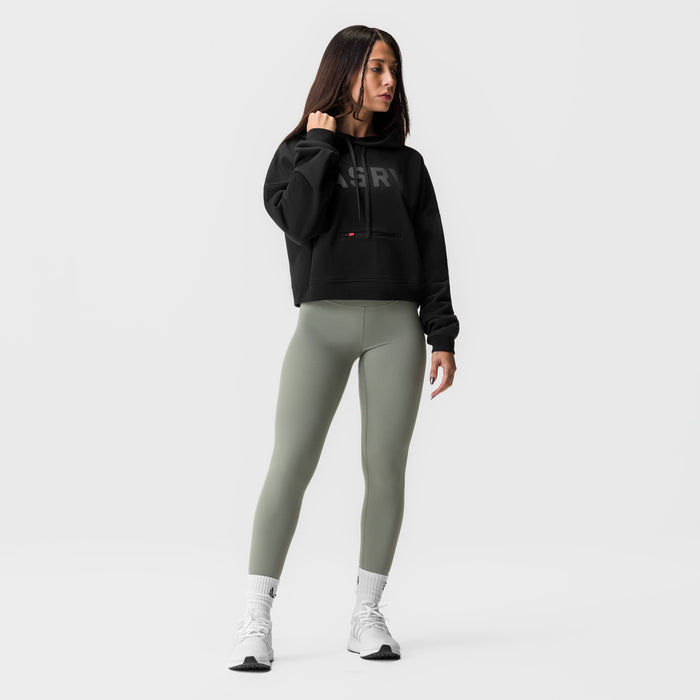 Black cropped hoodie styled with sage green leggings and white socks, front view on model