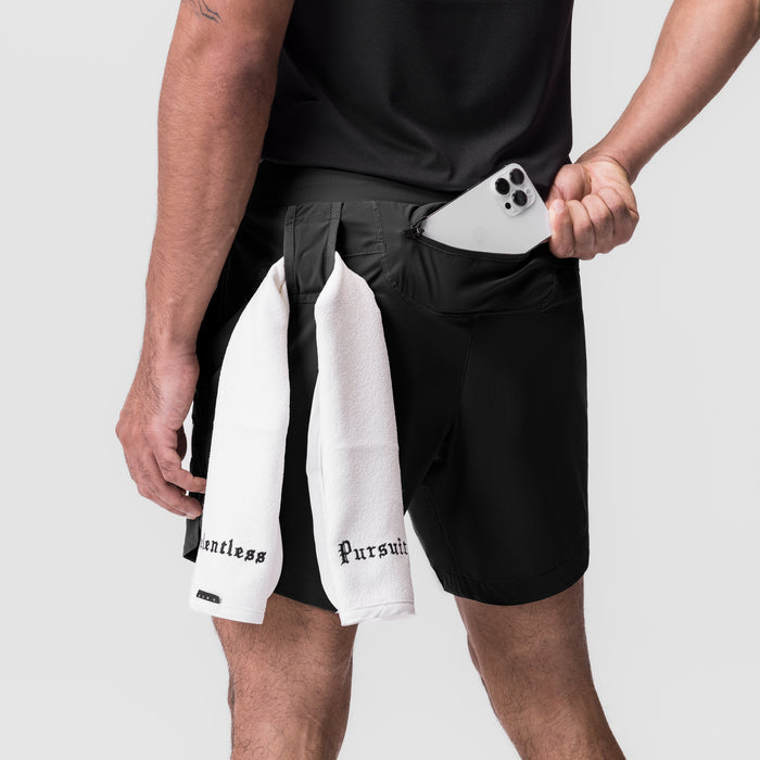 Black 7" linerless shorts worn with white towel, model holding white phone
