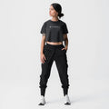 ASRV Tonal cropped training tee in black, worn with cargo joggers, front view