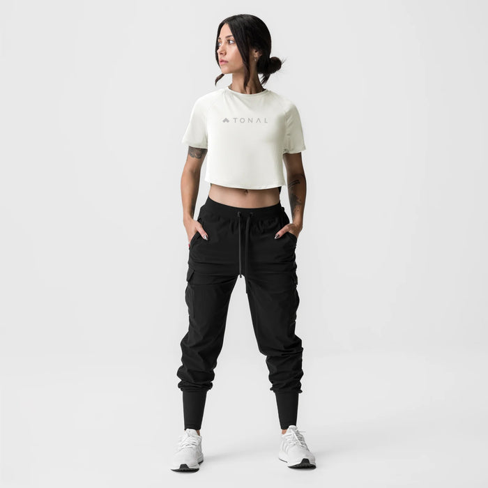 ASRV x Tonal Women's AeroSilver® Cropped Training Tee in ivory cream, worn with black cargo joggers