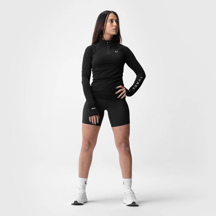 Black performance quarter zip long sleeve top and shorts worn by model, front view standing pose