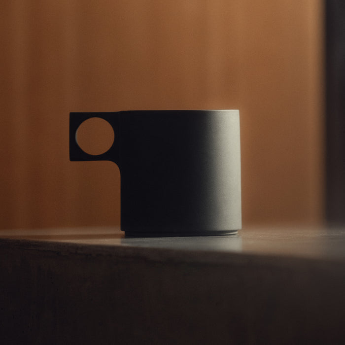 flatlay ASRV x Walden ceramic mug in black with tan handle, side view