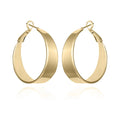 The Vince Camuto Band Thick Hoop Earrings feature classic gold-tone, wide smooth bands with latch-back clasps, shown against a white background.
