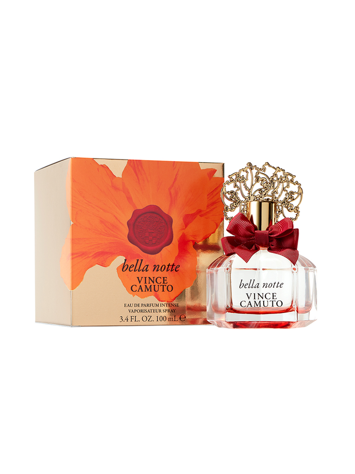 A bottle of Vince Camuto’s Bella Notte 3.4 oz Eau de Parfum Spray, adorned with an ornate gold cap and a red bow, sits beside its matching box decorated with a bold red flower design.