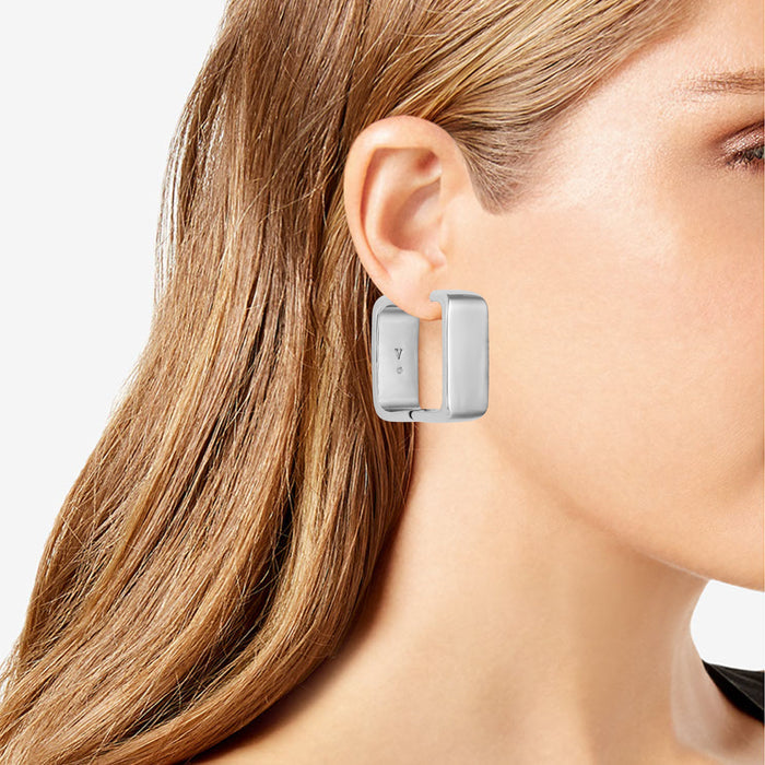 A model wears Vince Camuto Brass Rectangle Hoop Earrings in a polished silver finish, shown in close-up profile against a white background.