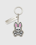 Introducing the CLASSIC BUNNY KEYCHAIN - B6A372E200 from Psycho Bunny, a fashionable metal accessory showcasing a cartoon bunny skull and crossbones design with distinctive pink ears. This practical everyday keychain features a sleek rectangular tag engraved with "Psycho Bunny." Complemented by a silver-colored chain and keyring, it adds a chic touch to your essentials.
