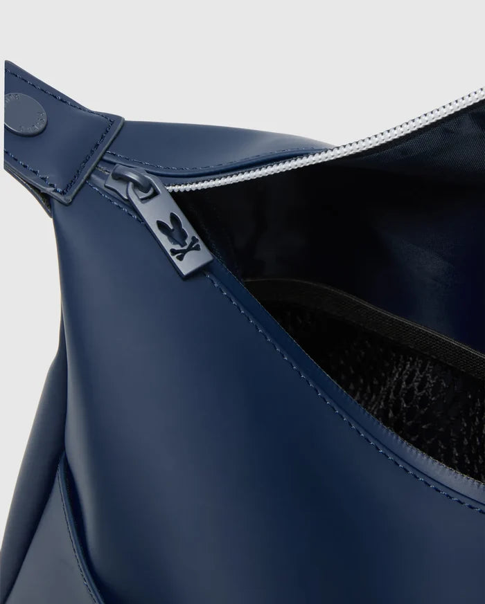 Classic Bunny Toiletry Kit in smooth navy blue material, featuring a white-toothed zipper with a metallic Psycho Bunny skull logo pull, a branded snap, and an interior mesh pocket.
