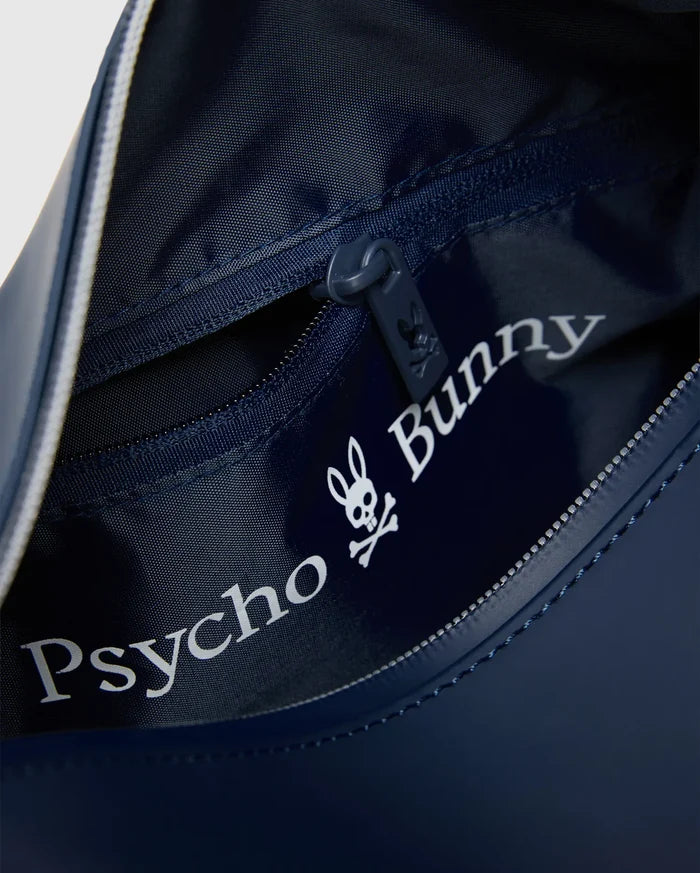 Navy blue Classic Bunny Toiletry Kit with smooth exterior, textured navy interior, zippered main compartment, internal pocket, and large white Psycho Bunny skull logo print, a small bunny skull on the zipper pull.