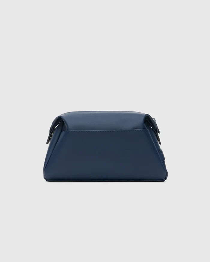 CLASSIC BUNNY TOILETRY KIT, a sleek navy blue travel bag with a smooth, matte finish. It features a structured rectangular shape, rounded edges, and a secure top flap closure, embodying refined streetwear style.