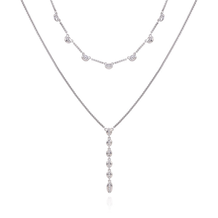 Two delicate silver necklaces from Vince Camuto’s Crystal Layered Necklace set—crafted with elegant jewelry appeal—feature silvertone chains: one adorned with evenly spaced small oval charms, the other showcasing a vertical drop pendant with multiple petite ovals, both beautifully displayed against a white background.