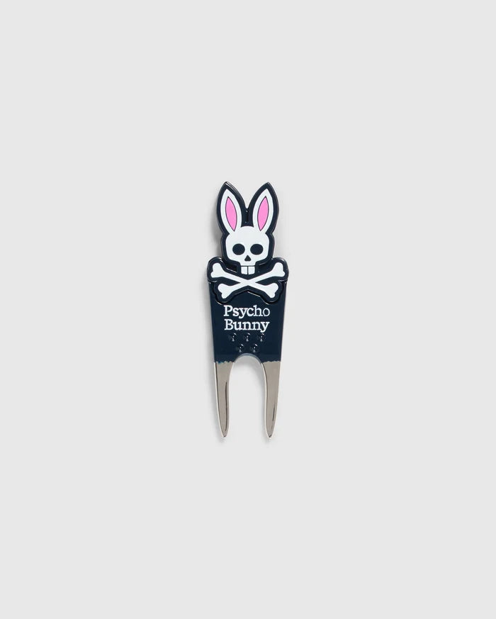 Image of a DIVOT TOOL - B6A699C200 from Psycho Bunny with a design featuring a skull with bunny ears and the text "Psycho Bunny" underneath. The tool has two prongs at the bottom, and the skull and ears are in black, white, and pink. A perfect addition to golf gifts, this tool also comes with a magnetic ball marker. The background is plain gray.
