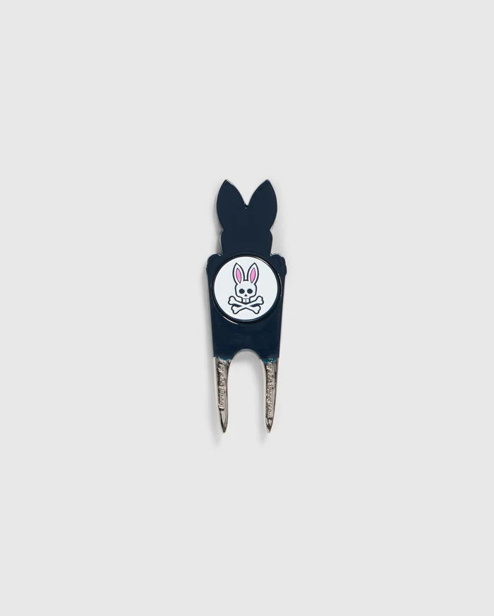 A Psycho Bunny DIVOT TOOL - B6A699C200 featuring a black handle with a white circular logo. The logo shows an illustration of a bunny head with crossed bones underneath. The two prongs of the tool are metal, and it includes a magnetic ball marker. Ideal for those seeking unique golf gifts.