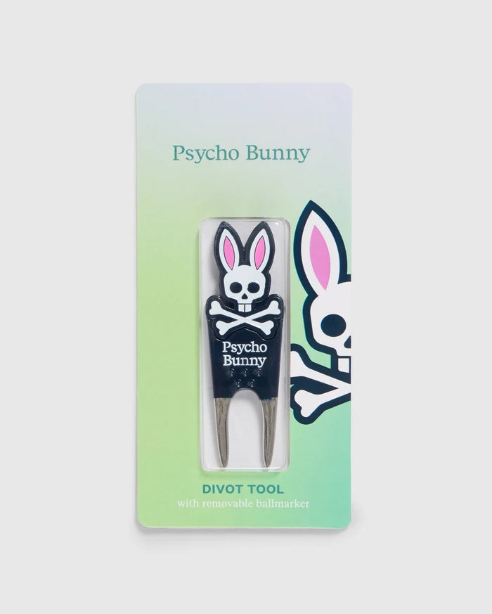 A Psycho Bunny branded DIVOT TOOL - B6A699C200 with a removable magnetic ball marker is displayed in its packaging. The tool features a bunny logo with crossbones and the text "Psycho Bunny" below it. The packaging has a green gradient background and a larger bunny logo on the right side, making it perfect for golf gifts.