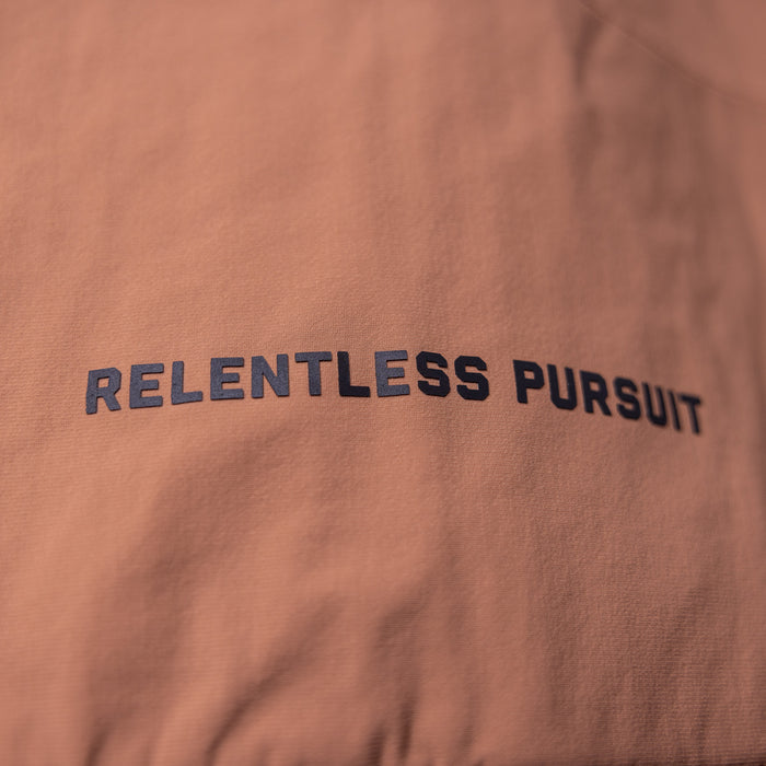 FA'22 Insulated Gilet Vest in rust, close-up detail of 'Relentless Pursuit' text on fabric
