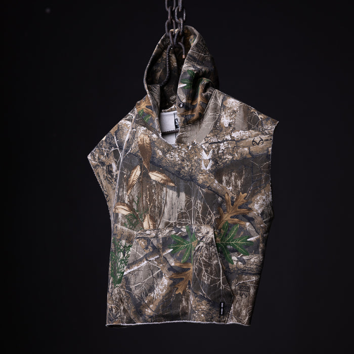 FA'23 Raw Hem Cutoff Hoodie in realtree camo, hanging from chain against black background