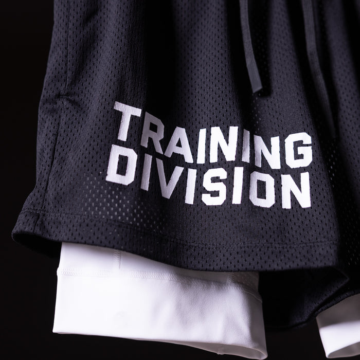 FA'23 Training Division mesh shorts in black worn by model, showing white underlay and embroidered logo detail