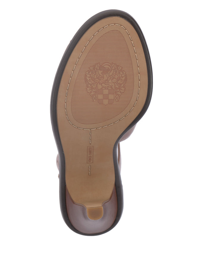 The underside of the Vince Camuto Frasper Shootie reveals a light tan sole with visible stitching, a coat of arms design embossed at the center, and a small rectangular label near the arch—details that highlight both craftsmanship and comfort similar to shoes featuring a cushioned footbed.