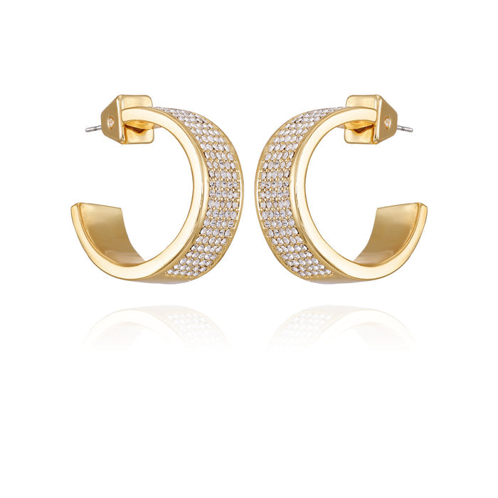 The Vince Camuto Goldtone Crystal C Hoop Earrings showcase a thick band adorned with rows of shimmering crystals along the outer surface, beautifully displayed on a white background with a mirrored reflection beneath—these modern earrings lend sophisticated style to any ensemble.