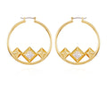 The Vince Camuto Goldtone Floating Crystal Hoop Earrings showcase four geometric pyramid shapes at the base, with a clear faceted crystal stone accentuating the center. This modern and symmetrical design is complemented by a lustrous goldtone band, beautifully presented against a plain white background.