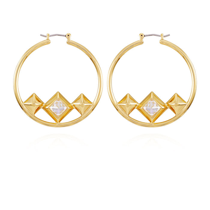 The Vince Camuto Goldtone Floating Crystal Hoop Earrings showcase four geometric pyramid shapes at the base, with a clear faceted crystal stone accentuating the center. This modern and symmetrical design is complemented by a lustrous goldtone band, beautifully presented against a plain white background.
