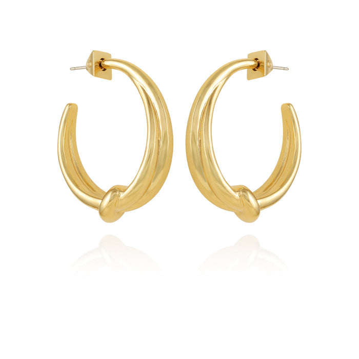A pair of Vince Camuto Goldtone Open Knotted Hoop Earrings, featuring a chunky, C-shaped hoop with a twisted open knotted design, are displayed upright on a white background with a subtle reflection below, highlighting their bold contemporary style.
