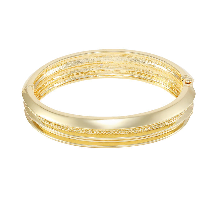 The Vince Camuto Goldtone Textured Hinge Bracelet features an intricate textured design with beaded details and a secure hinged closure, beautifully displayed on a white background.